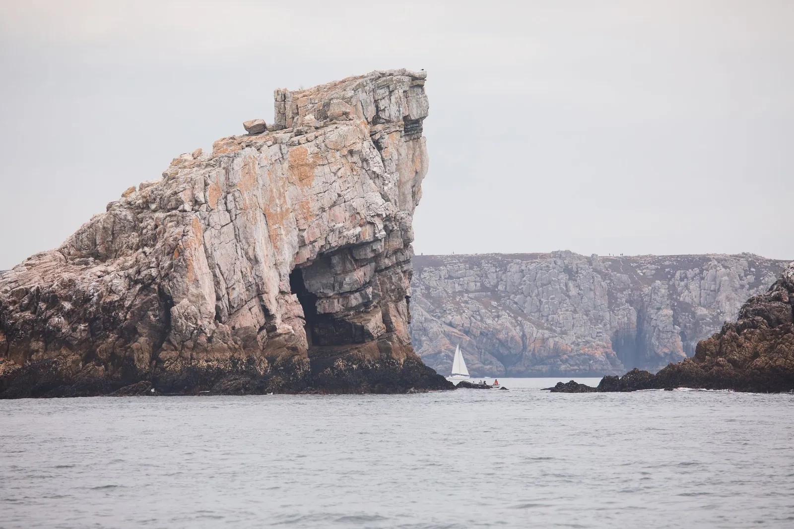 Falaises rocheuses de la presqu’île de Crozon avec un voilier au large