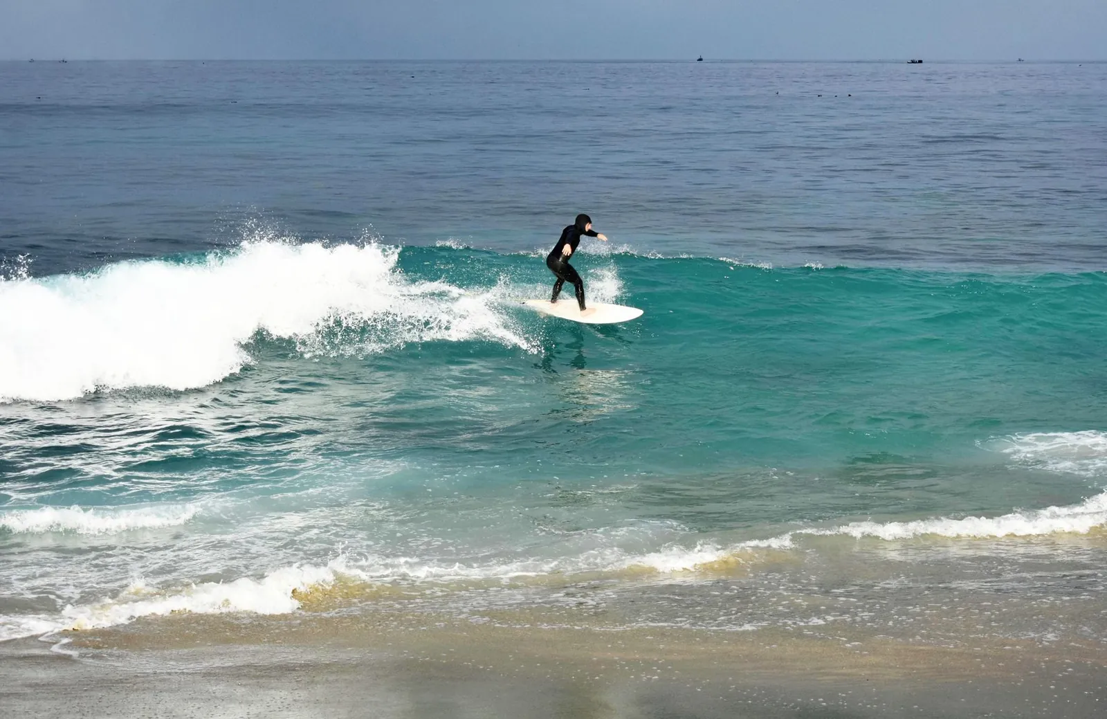 Un surfeur évolue sur une vague par temps clair